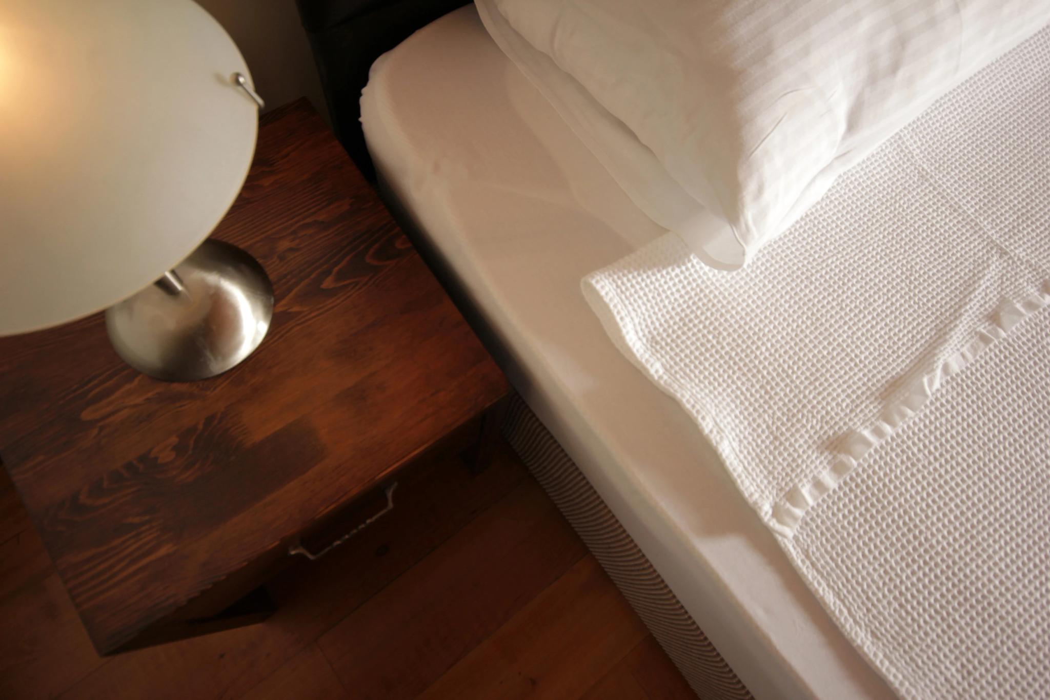 Détail de la literie et table de chevet dans une chambre de l'hôtel 4 étoiles San Andrea